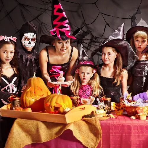 Παιδιά με στολές Halloween γύρω από γιορτινό τραπέζι στο φροντιστήριο